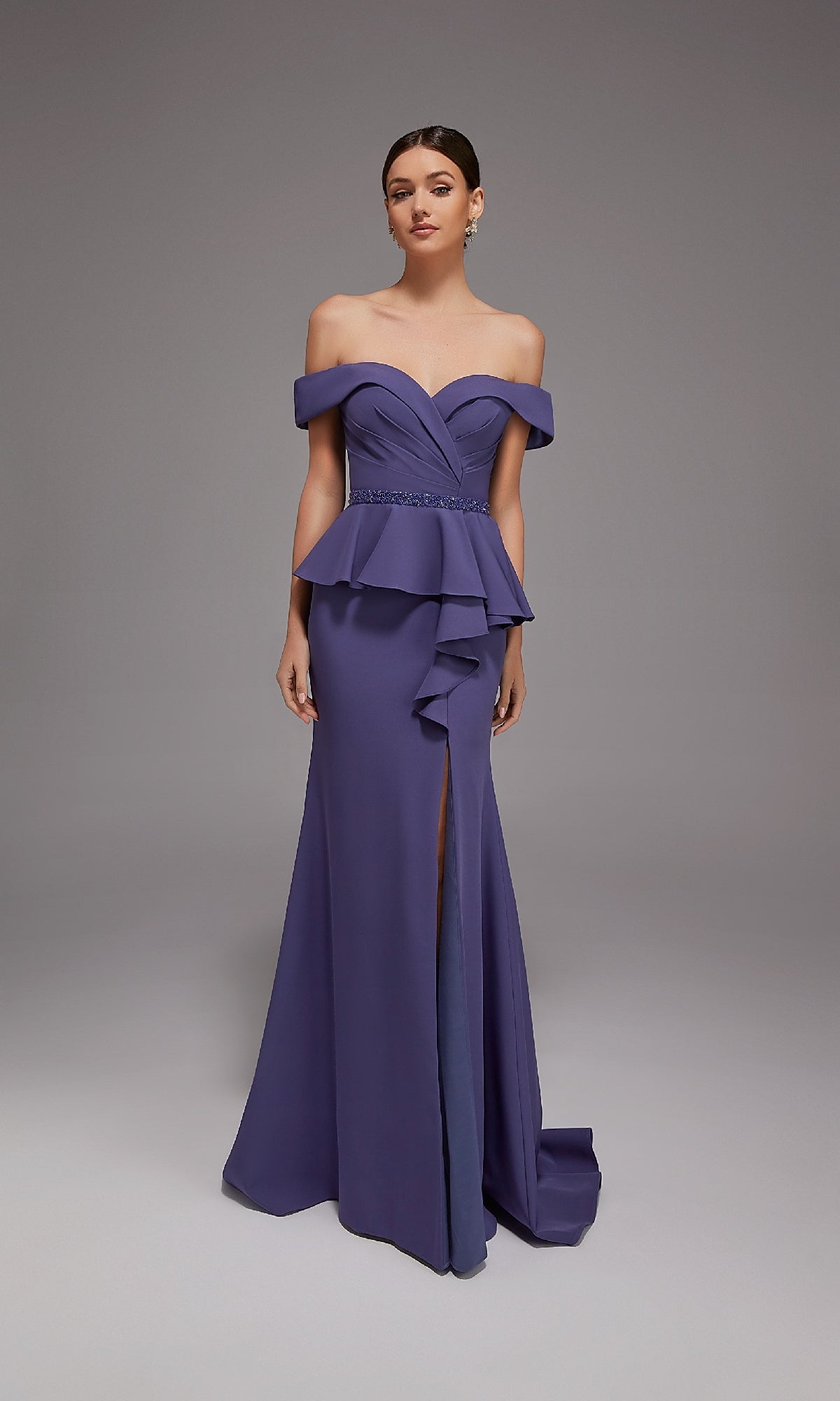 A woman models the Alyce 27829 long formal dress, featuring off-the-shoulder sleeves, a peplum waist, and a front slit in purple—ideal for special occasions—against a plain gray background.